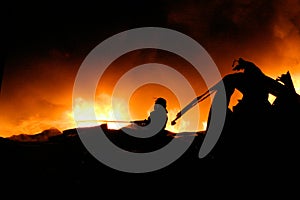 Silhouette of Firemen fighting a raging fire