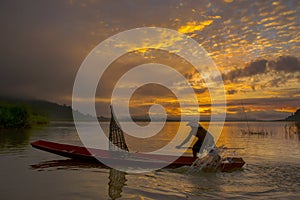 Silhouette fisherman of Bangpra Lake in action when fishing.