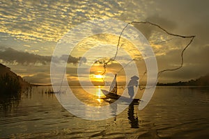Silhouette fisherman of Bangpra Lake in action when fishing.