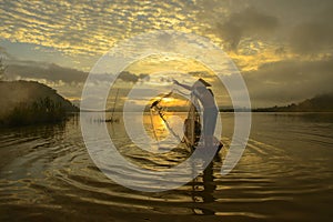 Silhouette fisherman of Bangpra Lake in action when fishing,