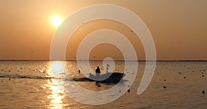 Silhouette of fisherman in a boat on the Beautiful sunset on the sea or river