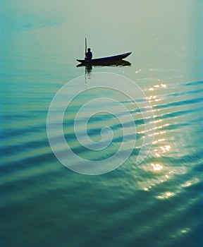 Silhouette of fisherman in boat on calm water