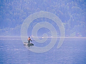 Silhouette of fisherman in the boat. Fisherman angling on the river.Top view summer. Summer nature river landscape. River grass su