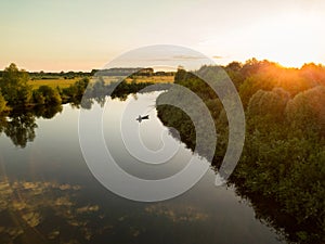 Silhouette of a fisherman in a boat on a river at sunset