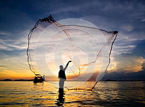 Silhouette of fisherman casting fishing net into the sea