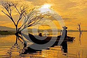 Silhouette fisherman on the fish boat on lake in the sunshine morning