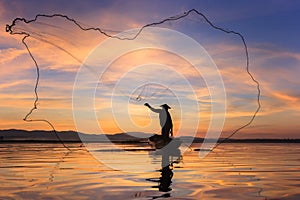 Silhouette fisherman on fishing boat setting net with sunrise