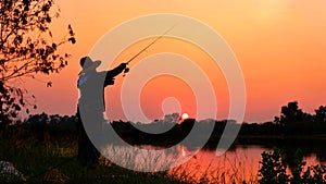 Silhouette fisherman fishing on river bank in sunset sky background