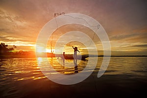 Silhouette Fisherman Fishing by using Net on the boat with sunshine in Thailand in the morning ,Nature and Culture concept