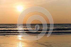 Silhouette of a fisherman man against the sunset and the sea. sand beach and wave, tinted with warm colors