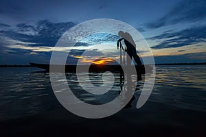 Silhouette fisherman with net at the lake.