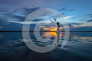 Silhouette fisherman with net at the lake