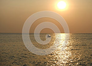 Silhouette of fisherman in sea at the golden sunset next to bright sun-glade on water. Phu Quoc, Vietnam