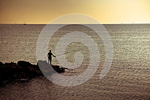 Silhouette of a fisherman at sunset in the Mediterranean Sea