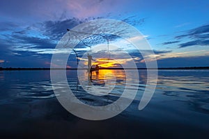 Silhouette of fisherman in wooden boat