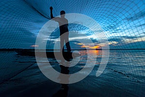 Silhouette of fisherman in wooden boat