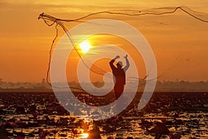 The silhouette fisherman working on the boat in lake for catching fish in sunrise, Culture of Thailand and Asia.