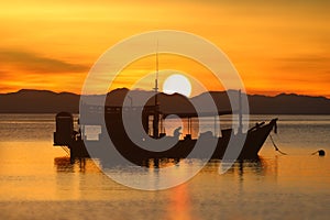 Silhouette of fishermen resting on their boats in the morning and the sun was rising behind