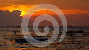 A silhouette of fishermen standing on rocks at sunset at Ba Keo Beach