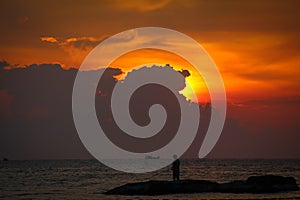 A silhouette of fishermen standing on rocks at sunset at Ba Keo Beach