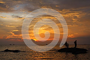 A silhouette of fishermen standing on rocks at sunset at Ba Keo Beach