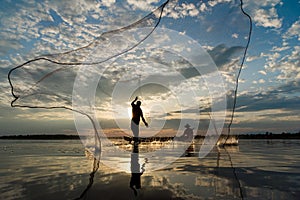 Silhouette of Fishermen throwing net fishing in sunset time at W
