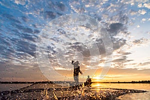 Silhouette of Fishermen throwing net fishing in sunset time at W