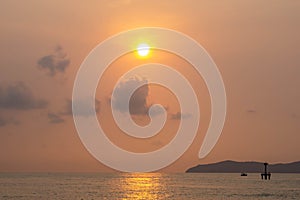 Silhouette of fishing boat and The lighthouse in the sea with eflection of the sun on the sea