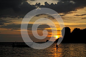 Silhouette of fishing boat and man at sunset on sea beach resort in Thailand, Krabi, Railey and Tonsai