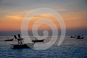 Silhouette of fishing boats against sunset