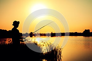 Silhouette of a fishing man on the river bank on the nature