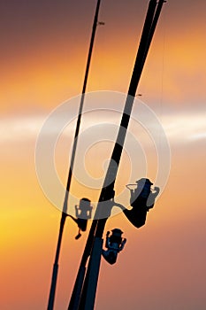 Silhouette of fishing rod with reels at sunset. Fishing equipment.