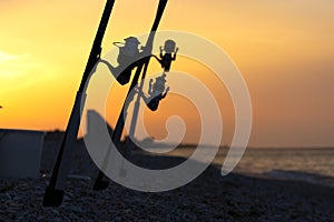 Silhouette of fishing rods with reels at sunset. Fishing equipment.