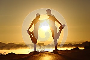 Silhouette of a fitness couple stretching at sunset