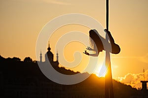 Silhouette of a flexible woman acrobat on aerial silk during a sunset on Kiev city background. concept of freedom and