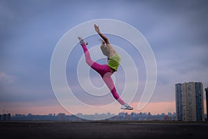 Silhouette of flexible woman jumping on the dramatic cloudscape during sunset. concept of excitement, freedom and