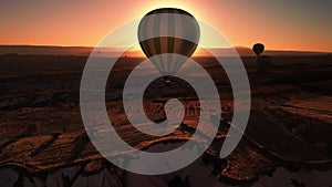 Silhouette of flying hot air balloons over valley in Cappadocia at sunset filmed by drone