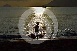 Silhouette of food vender against reflection of sun beam on the beach at dawn photo