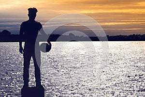 Silhouette of football soccer player boy standing and holding a ball on the beach