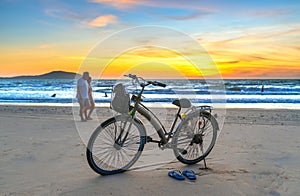 A silhouette of a foreign tourist couple happily walking together along a white sand beach