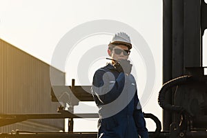 Silhouette of Foreman worker in hardhat and safety vest talking on two-way radio control loading containers box from cargo