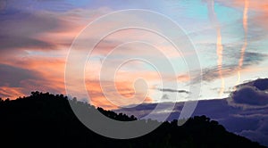 Silhouette of forest over the mountain against dramatic sunset