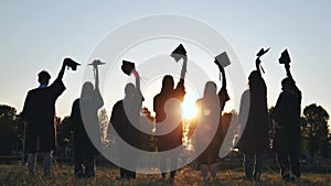 Silhouette of fresh graduates throwing their motarboard or trencher up in the air after their graduation.