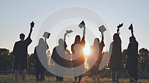 Silhouette of fresh graduates throwing their motarboard or trencher up in the air after their graduation.