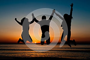 Silhouette of friends jumping on beach