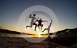 Silhouette of friends jumping at sunset on the beach