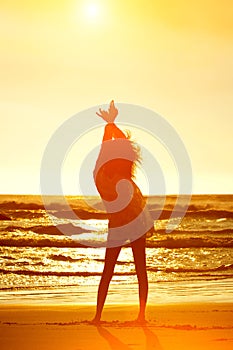 Silhouette full length young woman on beach with arms raised