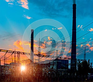 Silhouette of gas turbine electrical power plant against sunset.