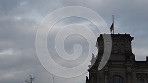 Silhouette of German flag waving on tower of Deutscher Bundestag building at dusk. Close up of historic ornamental