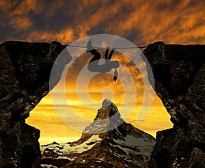 Silhouette girl climbs on a rope over an abyss. photo